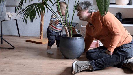 Je wordt anders ouder opa (opa met kleinkind achter plant an het kletsen)